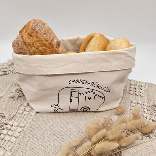 Schöner Naturfarbener Brotkorb aus Baumwollstoff, mit Aufgedrucktem Campingwagen und der Aufschrift Camper frühstück. der Druck kann leicht erfühlt werden, und ist einseitig. Die Obere Kante kann ja nach Inhalt umgeklappt werden. Er kann einfach zusammengefaltet und verstaut werden. Die Größe ist vergleichbar mit einem Mittleren Kochtopf.