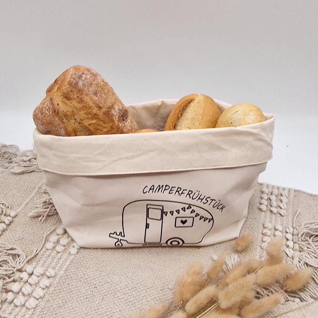 Schöner Naturfarbener Brotkorb aus Baumwollstoff, mit Aufgedrucktem Campingwagen und der Aufschrift Camper frühstück. der Druck kann leicht erfühlt werden, und ist einseitig. Die Obere Kante kann ja nach Inhalt umgeklappt werden. Er kann einfach zusammengefaltet und verstaut werden. Die Größe ist vergleichbar mit einem Mittleren Kochtopf.