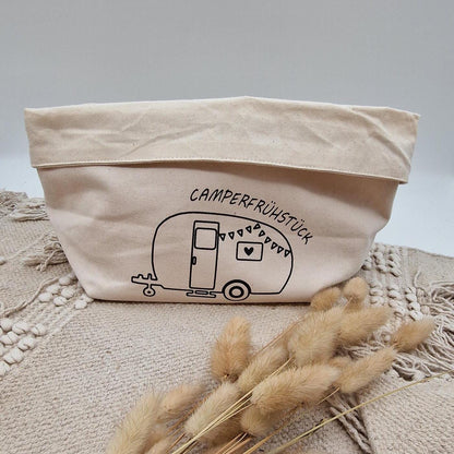 Schöner Naturfarbener Brotkorb aus Baumwollstoff, mit Aufgedrucktem Campingwagen und der Aufschrift Camper frühstück. der Druck kann leicht erfühlt werden, und ist einseitig. Die Obere Kante kann ja nach Inhalt umgeklappt werden. Er kann einfach zusammengefaltet und verstaut werden. Die Größe ist vergleichbar mit einem Mittleren Kochtopf.