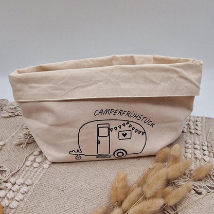 Schöner Naturfarbener Brotkorb aus Baumwollstoff, mit Aufgedrucktem Campingwagen und der Aufschrift Camper frühstück. der Druck kann leicht erfühlt werden, und ist einseitig. Die Obere Kante kann ja nach Inhalt umgeklappt werden. Er kann einfach zusammengefaltet und verstaut werden. Die Größe ist vergleichbar mit einem Mittleren Kochtopf.