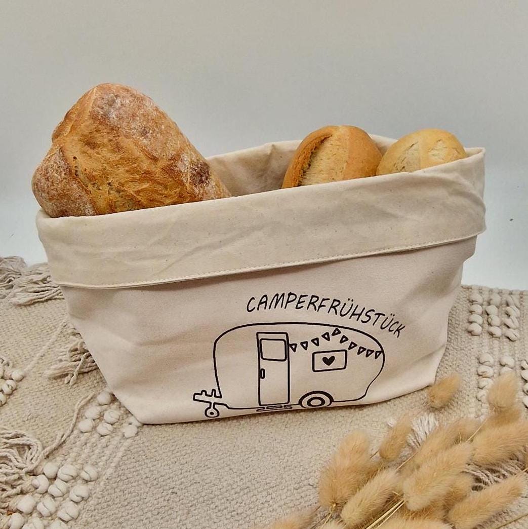 Schöner Naturfarbener Brotkorb aus Baumwollstoff, mit Aufgedrucktem Campingwagen und der Aufschrift Camper frühstück. der Druck kann leicht erfühlt werden, und ist einseitig. Die Obere Kante kann ja nach Inhalt umgeklappt werden. Er kann einfach zusammengefaltet und verstaut werden. Die Größe ist vergleichbar mit einem Mittleren Kochtopf.