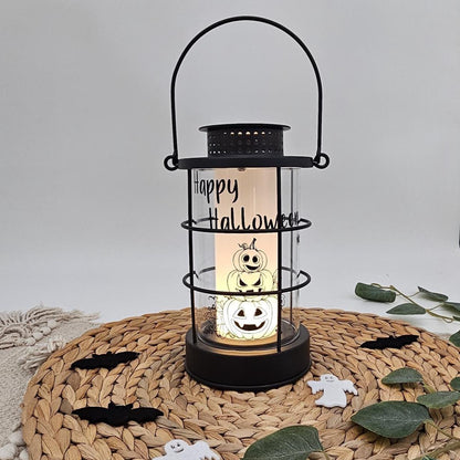 Schwarze Metall-Laterne mit Aufschrift „Happy Halloween“, niedlichem Kürbis-Turm Motiv und warm leuchtender LED-Kerze im Inneren auf Untersetzer.