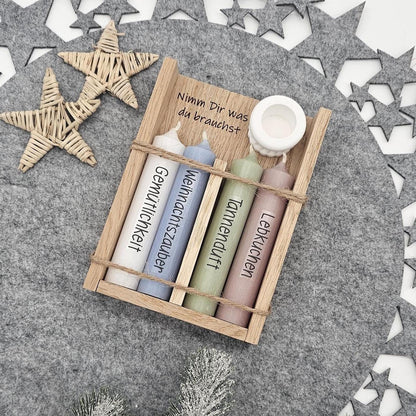 Weihnachtsgeschenkset aus der Vogelperspektive: Holzbox mit Gravur ‚Nimm Dir was du brauchst‘, vier Stabkerzen mit Aufschrift Gemütlichkeit, Weihnachtszauber, Tannenduft, Lebkuchen und weißer Kerzenständer.
